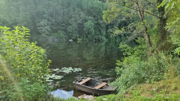 une barque sur le Lot à Cadrieu avec un pêcheur au loin sur une autre barque