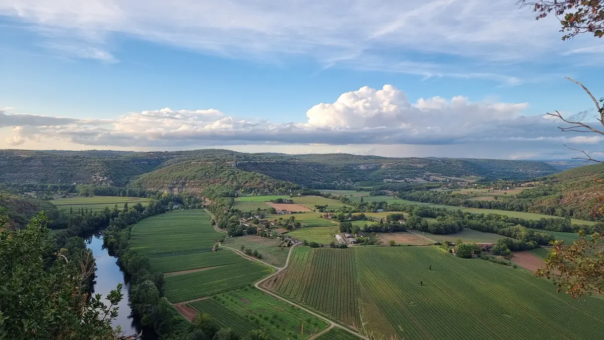 La vallée du Lot vue au Saut de la Mounine , on devine une boucle de la rivière, des champs, un immense nuage domine le vallée et de l'autre côté le causse du Quercy
